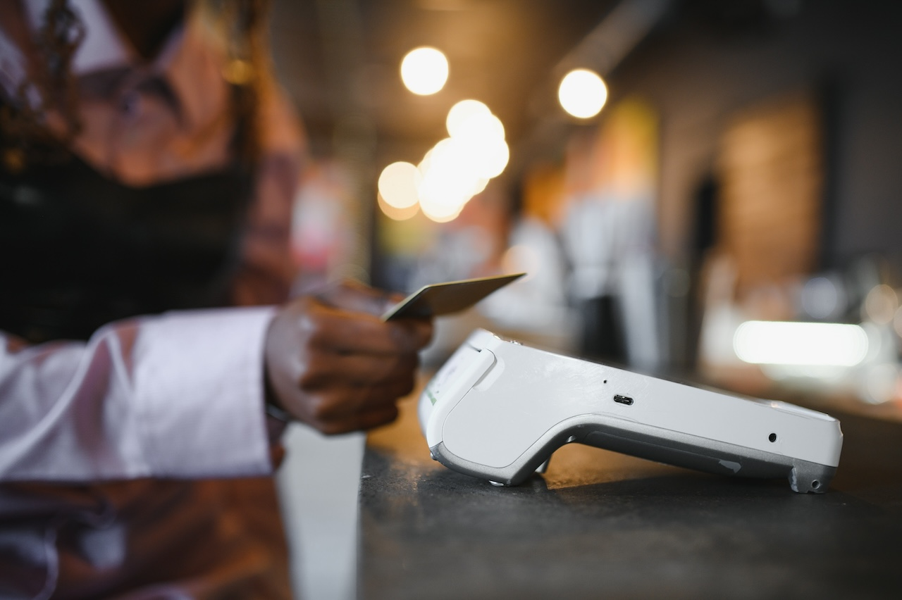 Business customer holding a credit card over a payment terminal